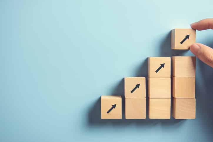 Hand arranging wooden blocks as a rising staircase. Indicating scalability in cloud computing.