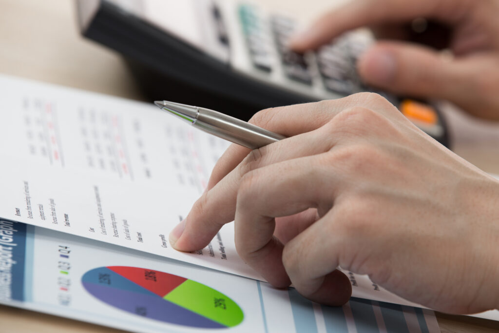 Closeup of a person working on a calculator, while going through a cost breakdown printout.